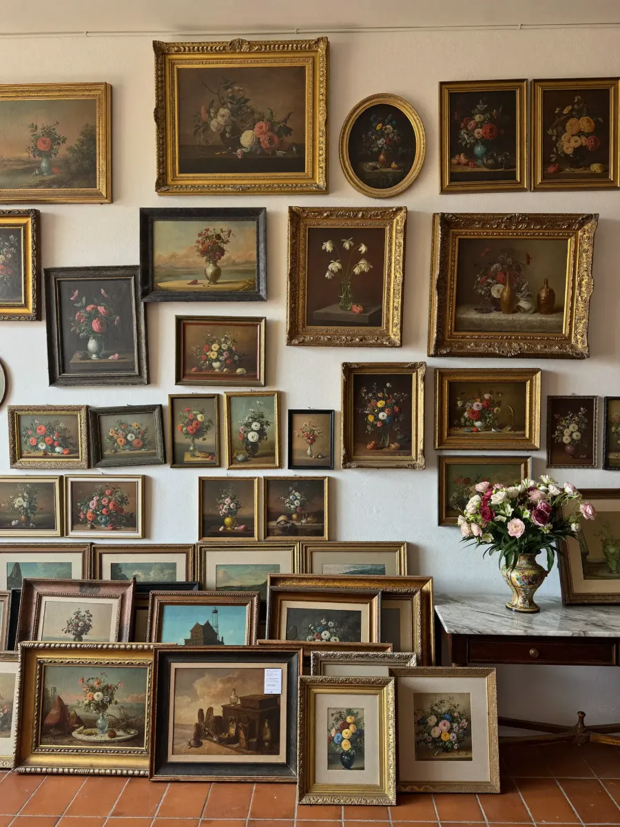 Salon wall of antique floral oil paintings in gilded frames