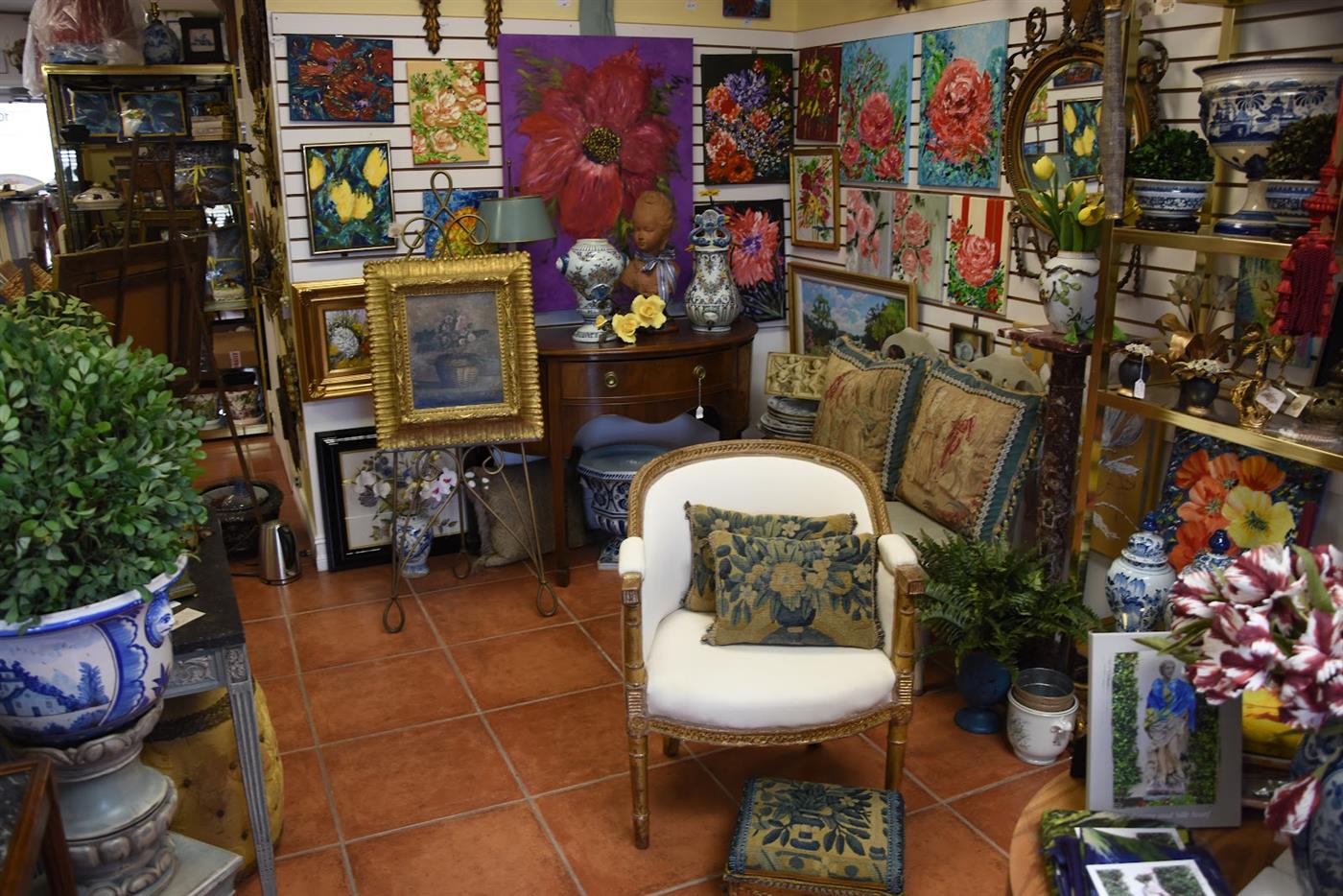 Salon-style wall of framed paintings above antique furniture