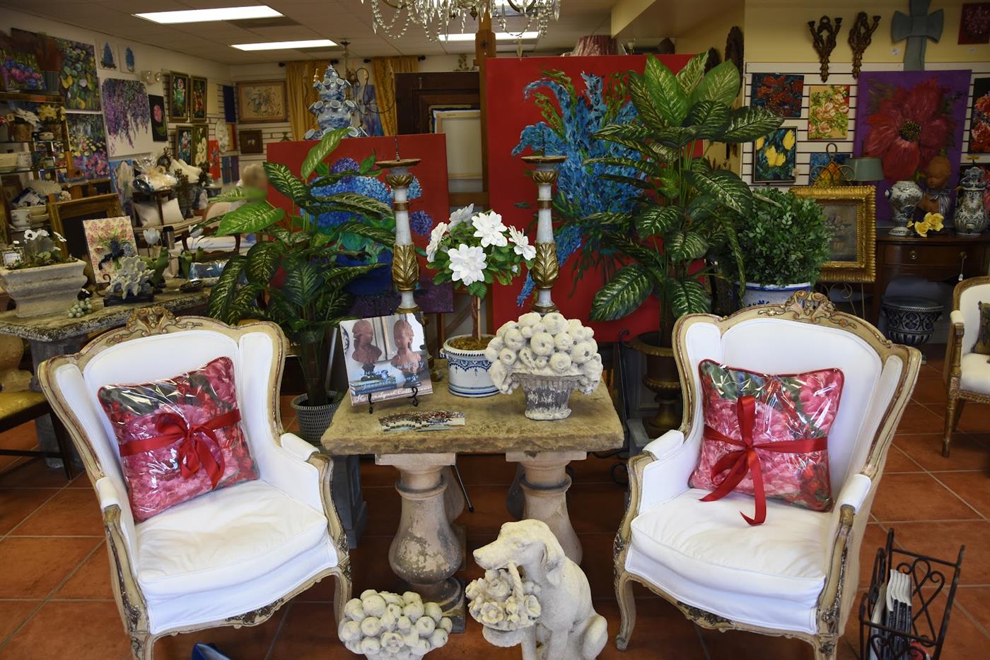 Inside the shop — antique bergère chairs and a stone table surrounded by art